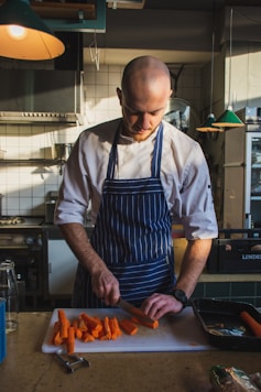 man slicing orange carrots
