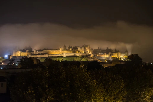 A misty medieval castle courtyard at dawn, bathed in soft golden light.