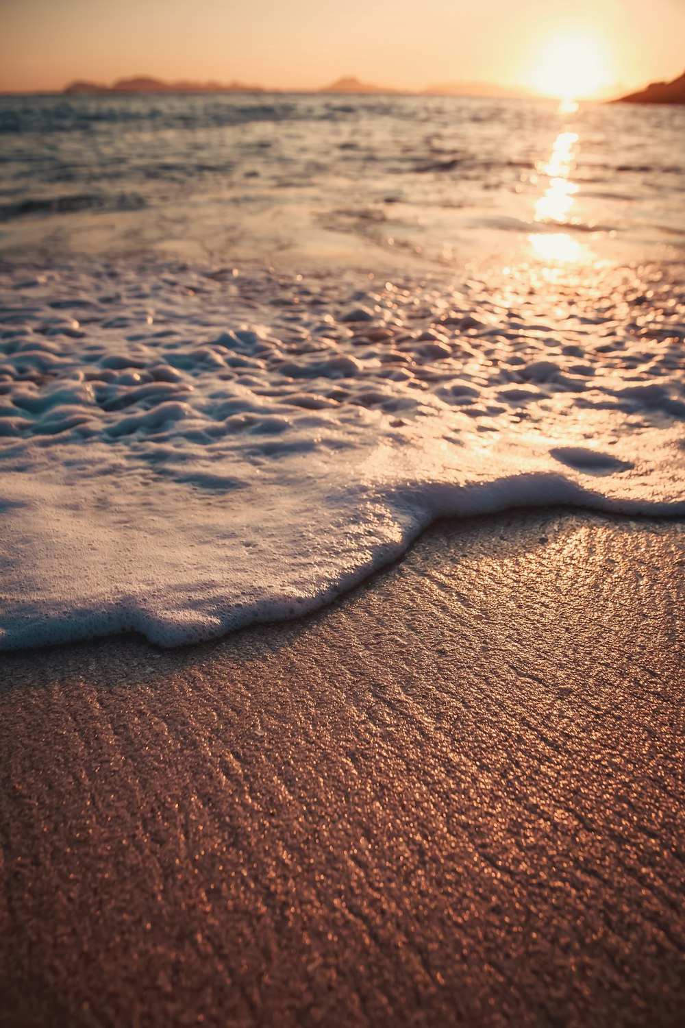 the sun is setting over the water at the beach