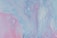 A vibrant abstract painting featuring a fluid mix of pastel colors. Swirling patterns of light blue, pink, and lavender create a dynamic and ethereal composition.
