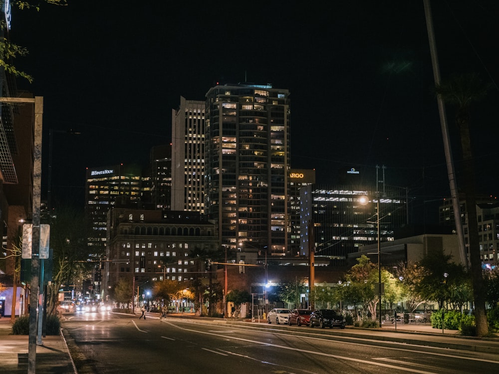 夜間の道路近くのライトアップされた高層ビルの写真を見る