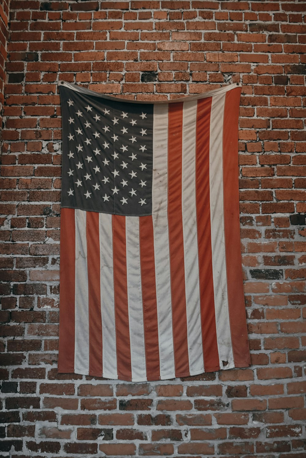 갈색 벽돌 벽에 걸려 있는 미국 국기