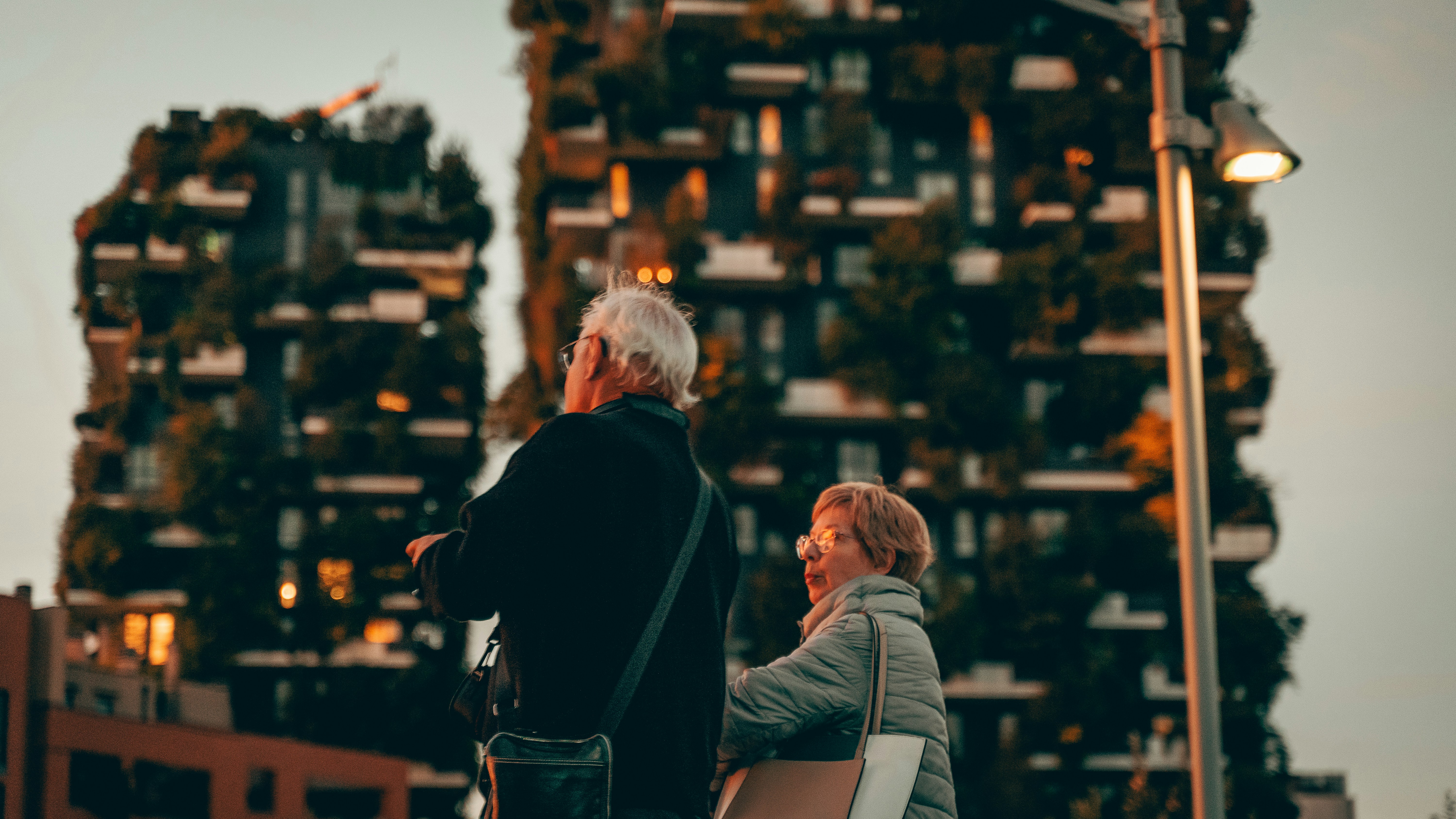 woman and man standing near hand rail with view of high-rise building