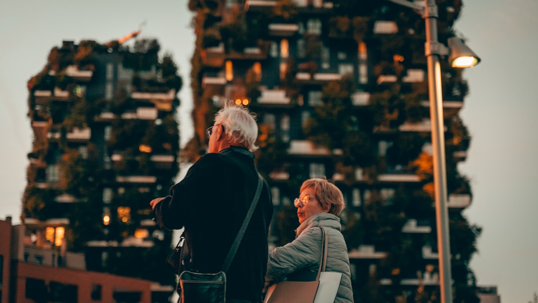 woman and man standing near hand rail with view of high-rise building