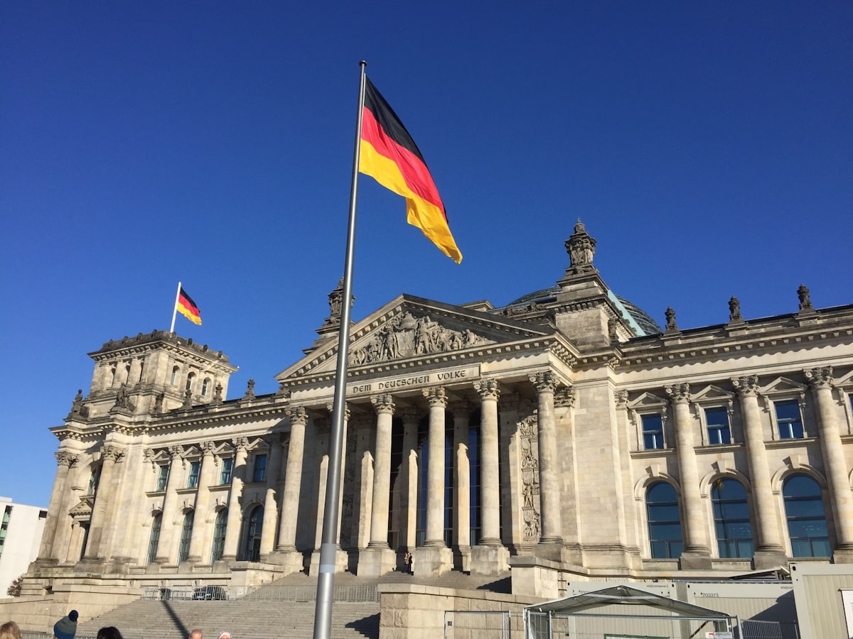 German flag flying on a pole in front of the Reichstag building in Berlin