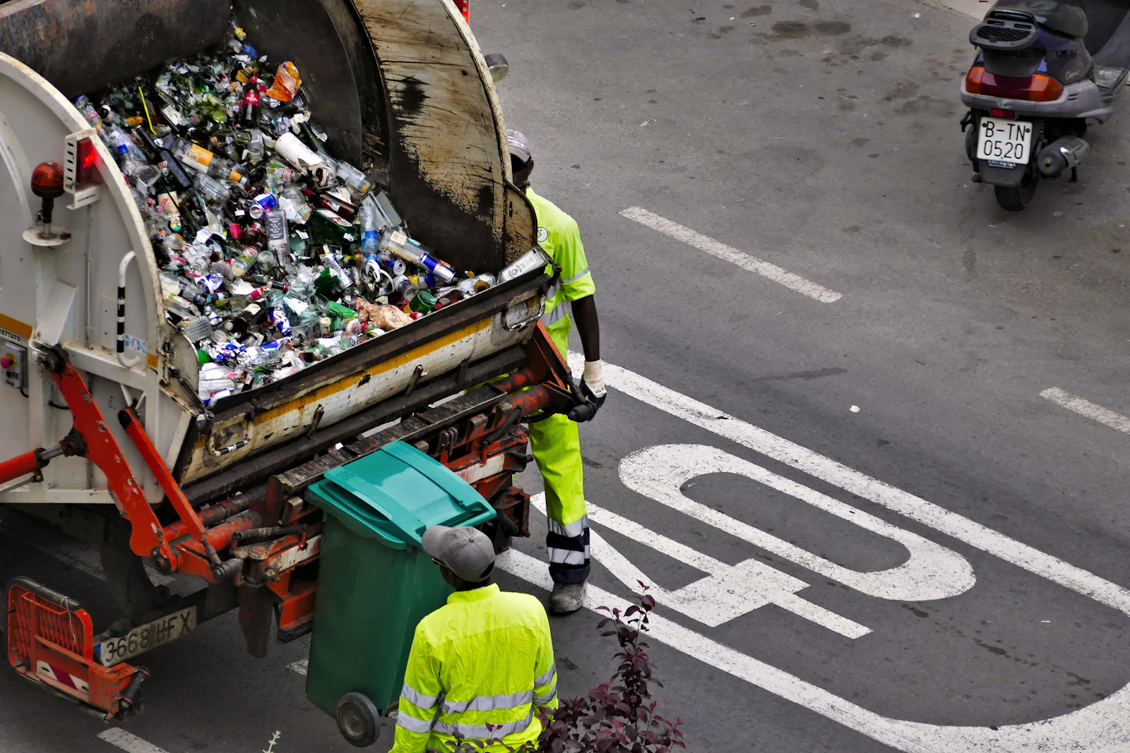 Workers collecting waste into a truck on a city street