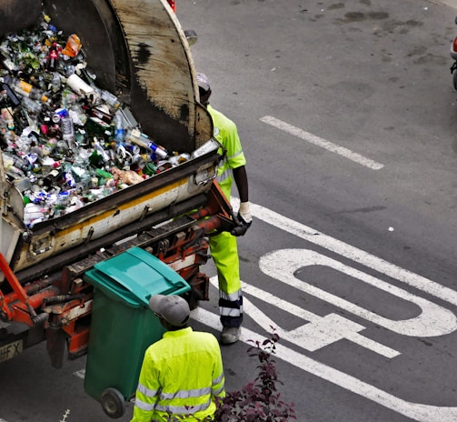 people collecting trash in garbage truck