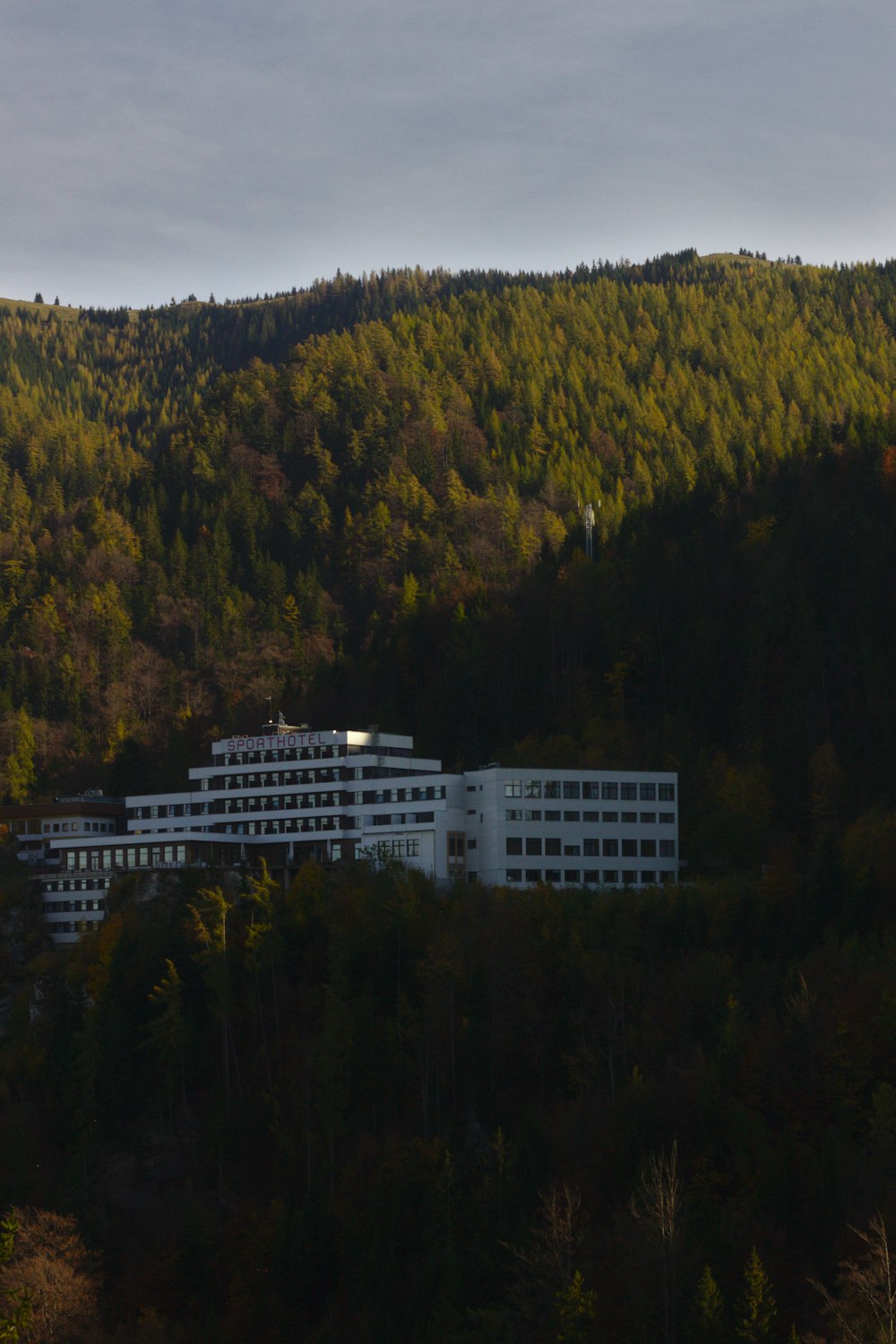 white concrete building on hill surrounded with trees
