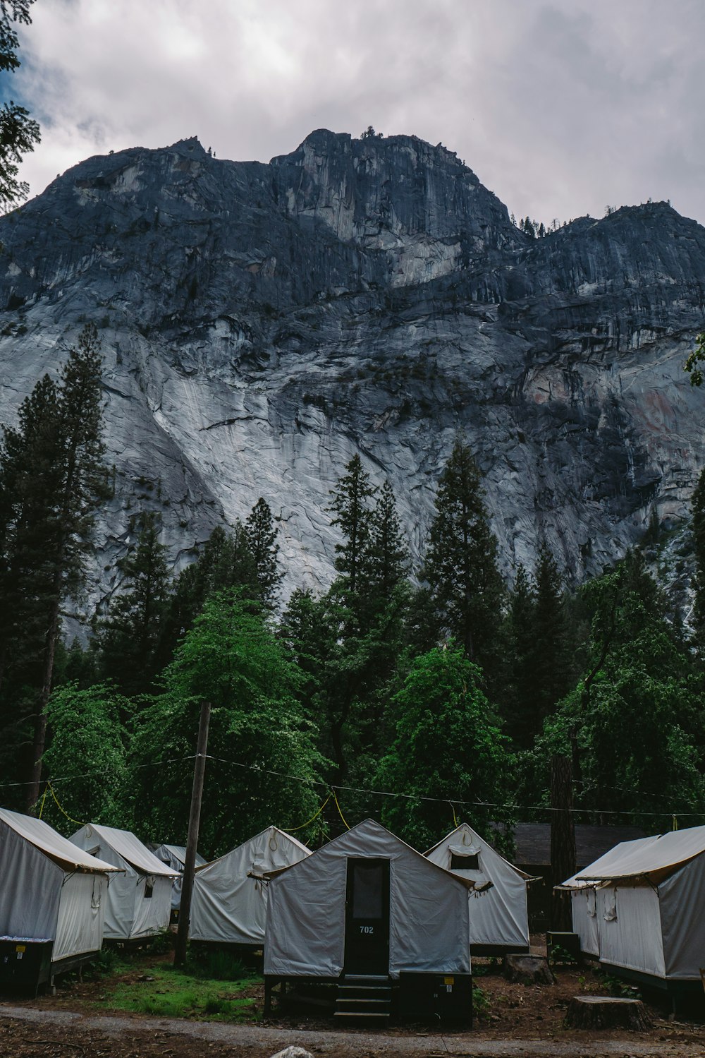 黒と灰色の山の下の木々の近くの白い家のテントの写真を見る