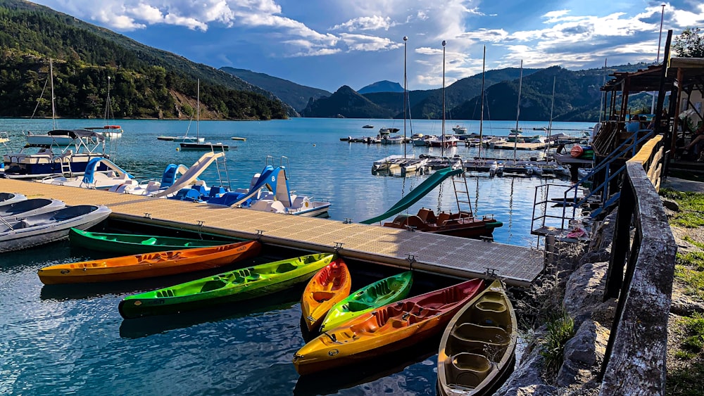 view photography of assorted-color canoes near dock and mountain during daytime