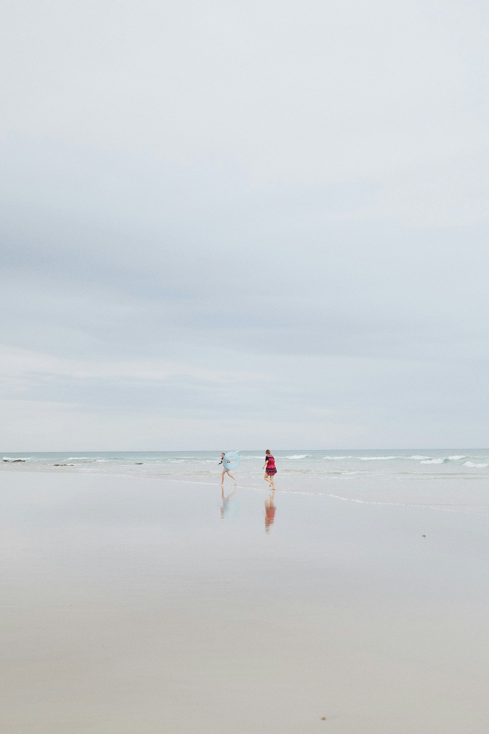 2 person on shore under white skies