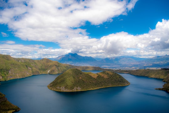 island in the middle of lake under blue and white skies in Cuicocha Ecuador