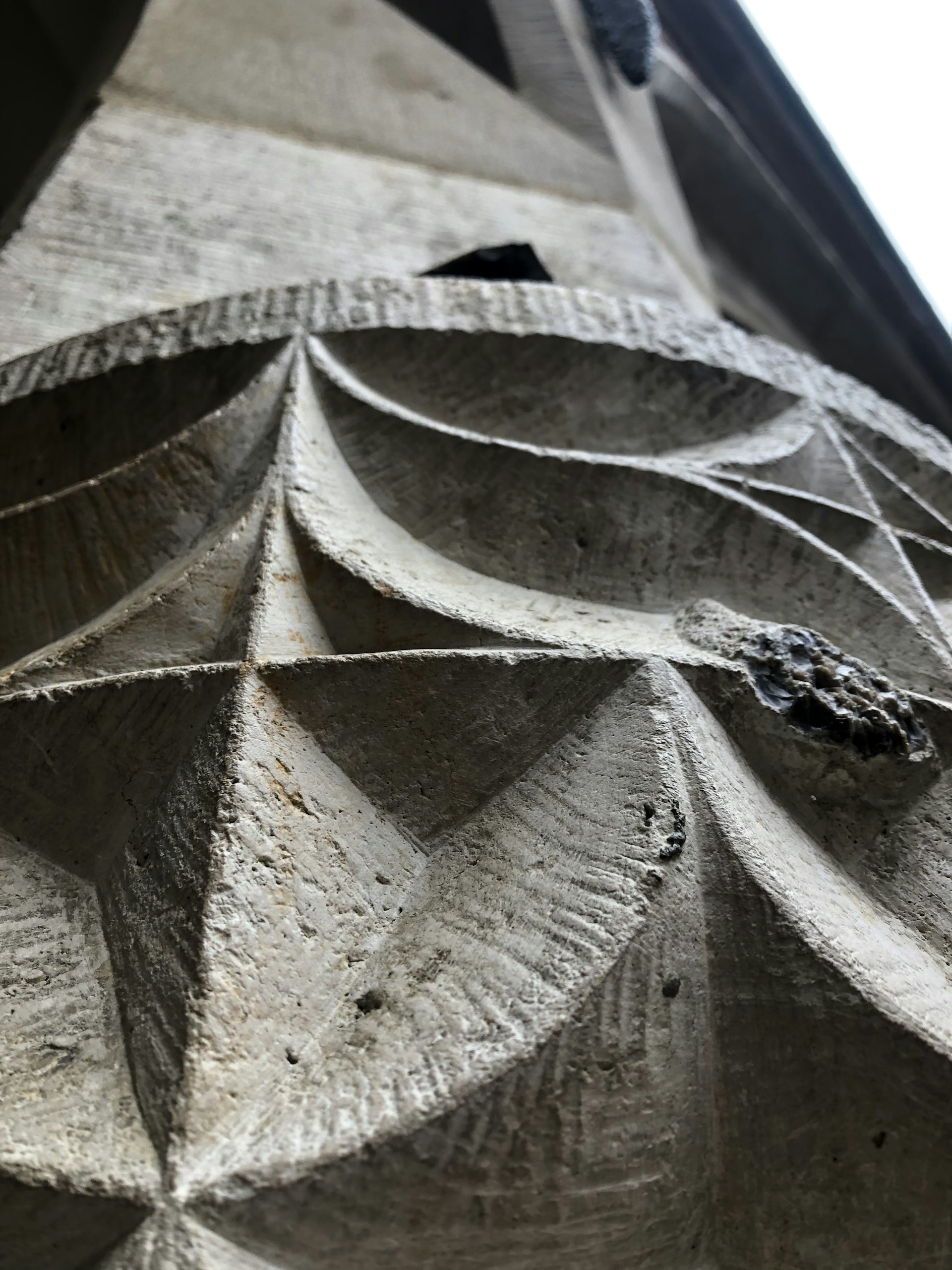 A close-up of a textured stone sculpture highlighting the intricate chisel marks and natural patterns.