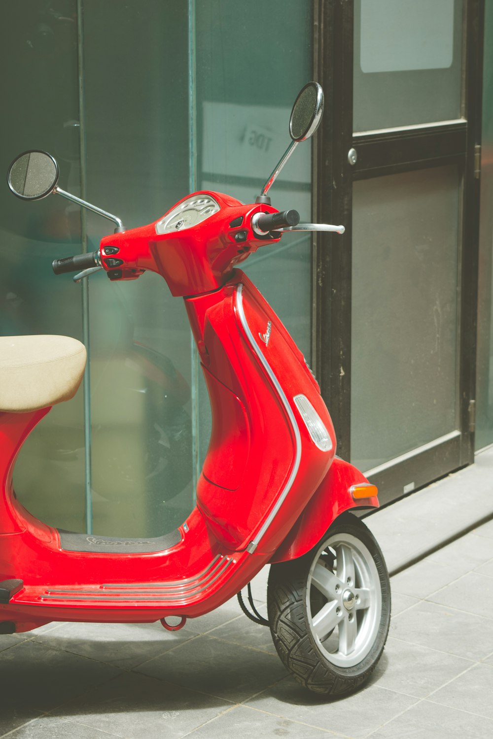 red and white motor scooter beside glass wall