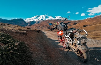 red standard motorcycle on soil pathway