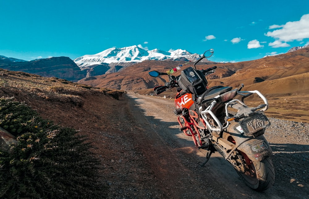 red standard motorcycle on soil pathway