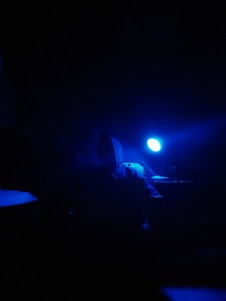 Close-up of a sleek black hoodie with electric blue accents, draped over a textured desk mat under soft shadow lighting.