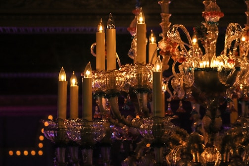 A technician carefully repairing a vintage chandelier with tools.