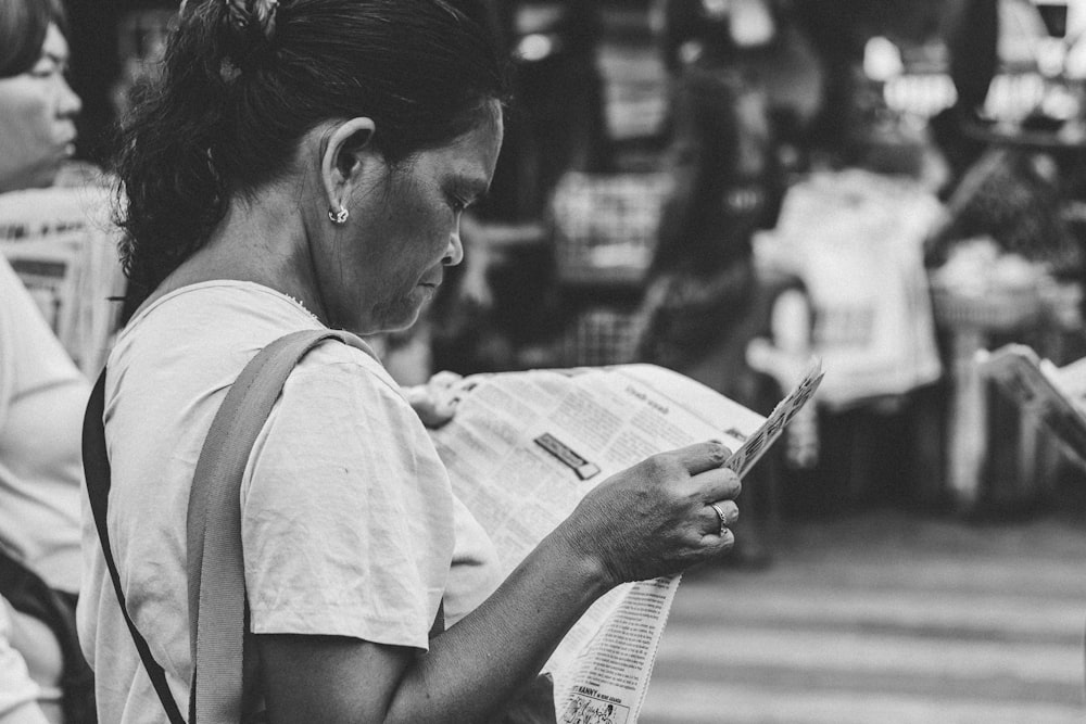 grayscale photo of woman reading newspaper