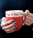 person holding white and red ceramic mug