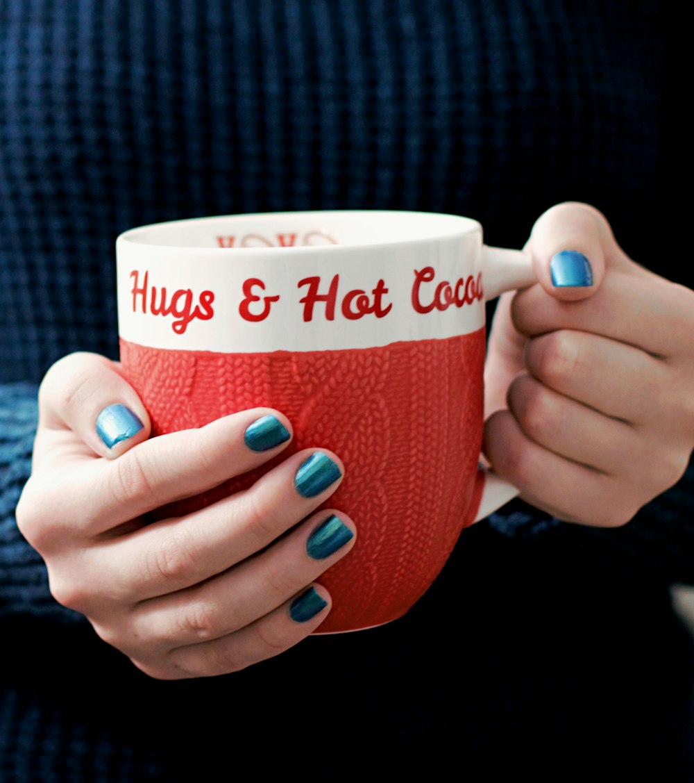 person holding white and red ceramic mug
