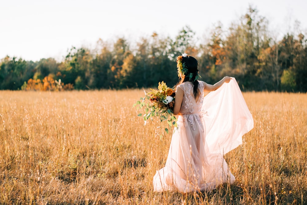 Mujer con vestido floral blanco que camina sobre el campo de hierba marrón