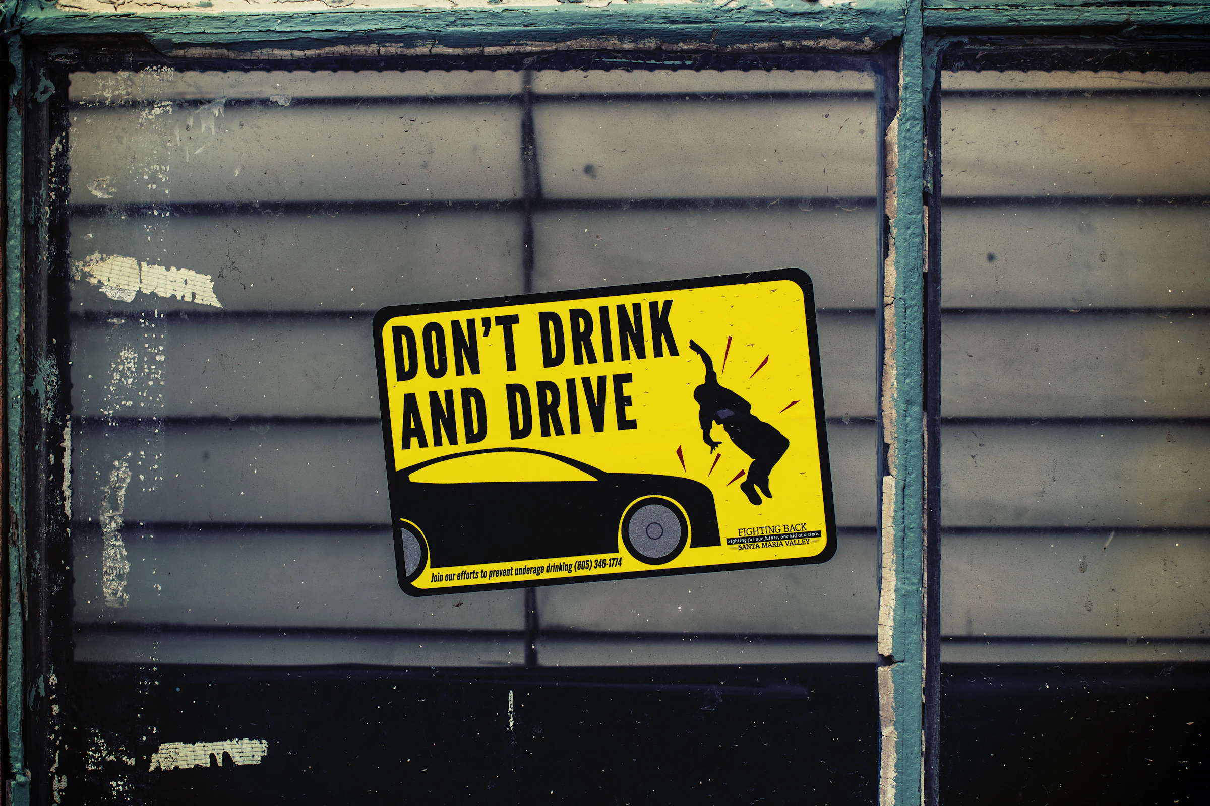 Sticker de prévention 'Don't Drink and Drive' sur une fenêtre vintage — symbole universel de la lutte contre la conduite sous influence