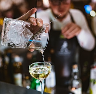 person pouring beverage in cocktail glass