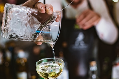 person pouring beverage in cocktail glass