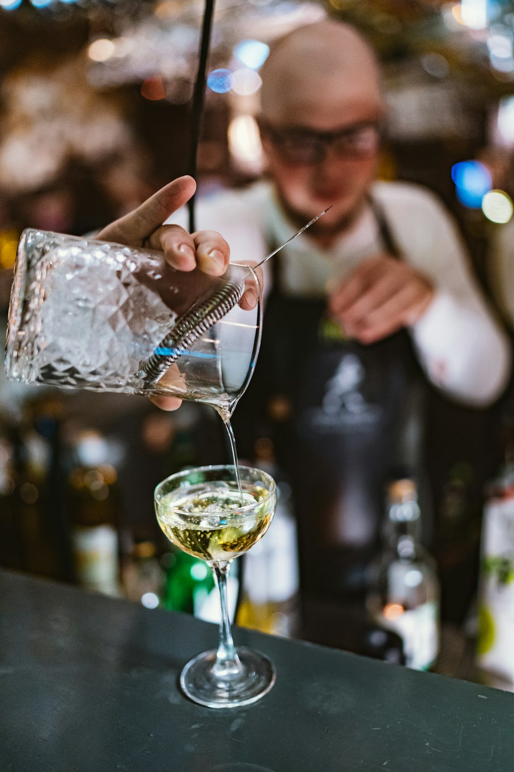 person pouring beverage in cocktail glass