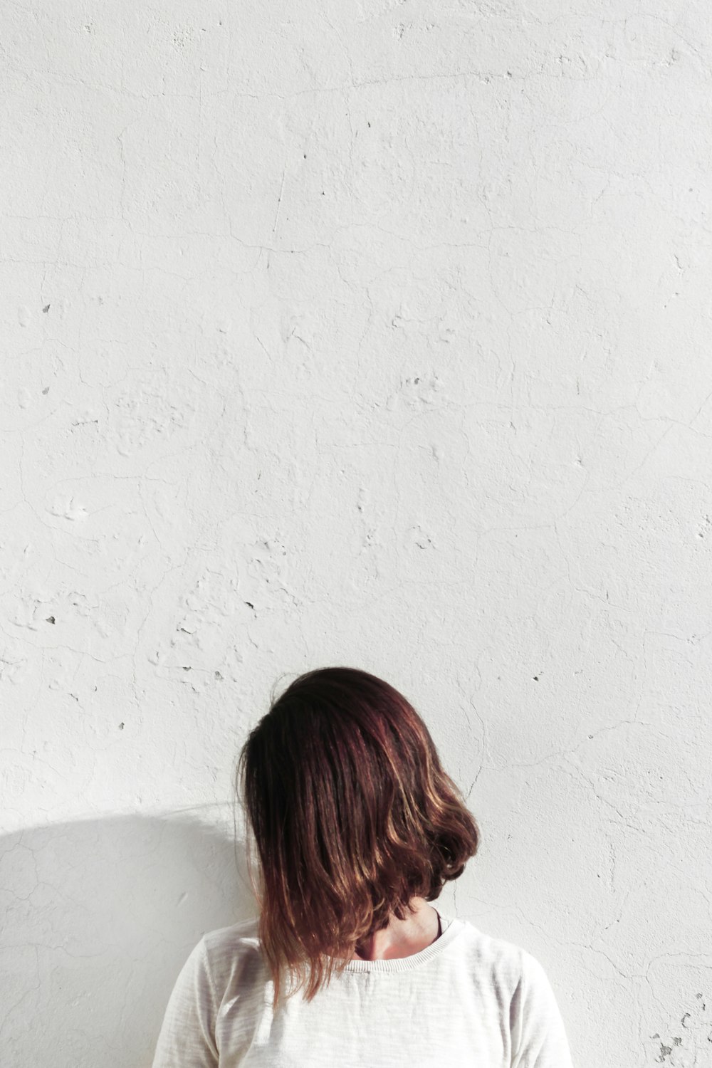 woman in white shirt leaning on wall during daytime