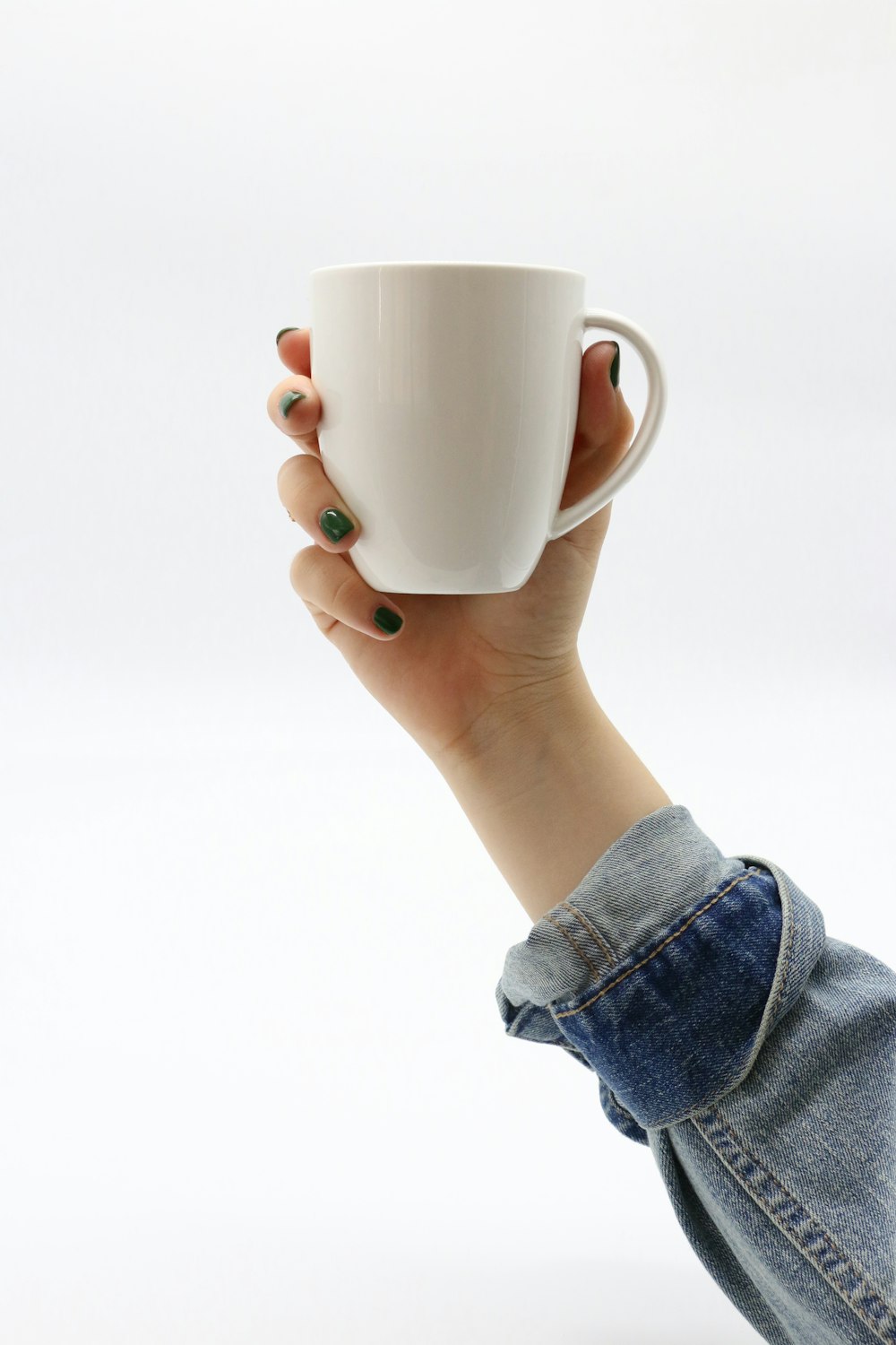 person in blue apparel holding white ceramic mug