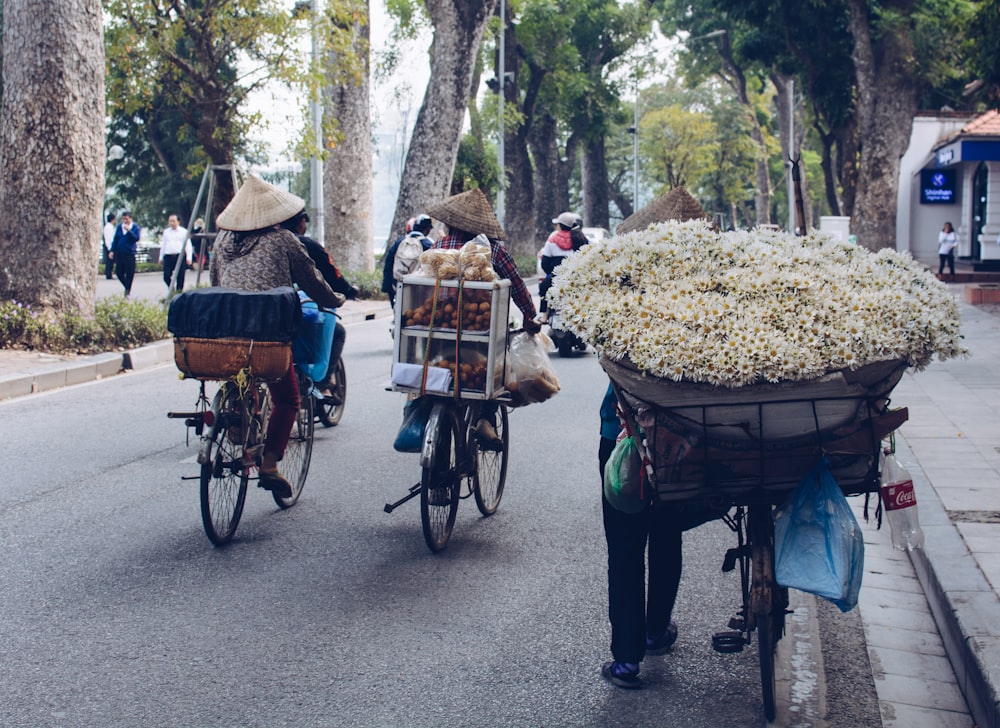 person holding bicycle carrying bunch of white flowers during daytime