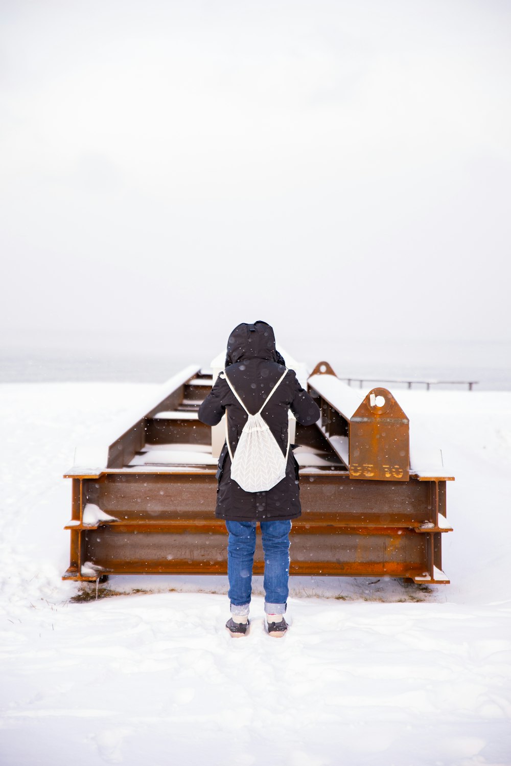 woman wearing black coat carrying white backpack