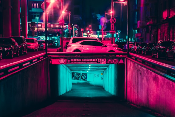 A neon-lit street scene at night with sleek cars parked under glowing signs, capturing the synth pop vibe of orldriftwave's car shows.