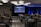 A conference room filled with attendees seated in rows facing a large screen displaying '#PRODUCTCON Los Angeles' along with sponsor logos. The room is dimly lit with bright blue accent lighting on the walls and ceiling, and people appear to be engaged and attentive.