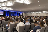 Conference speakers presenting on stage with an attentive audience.