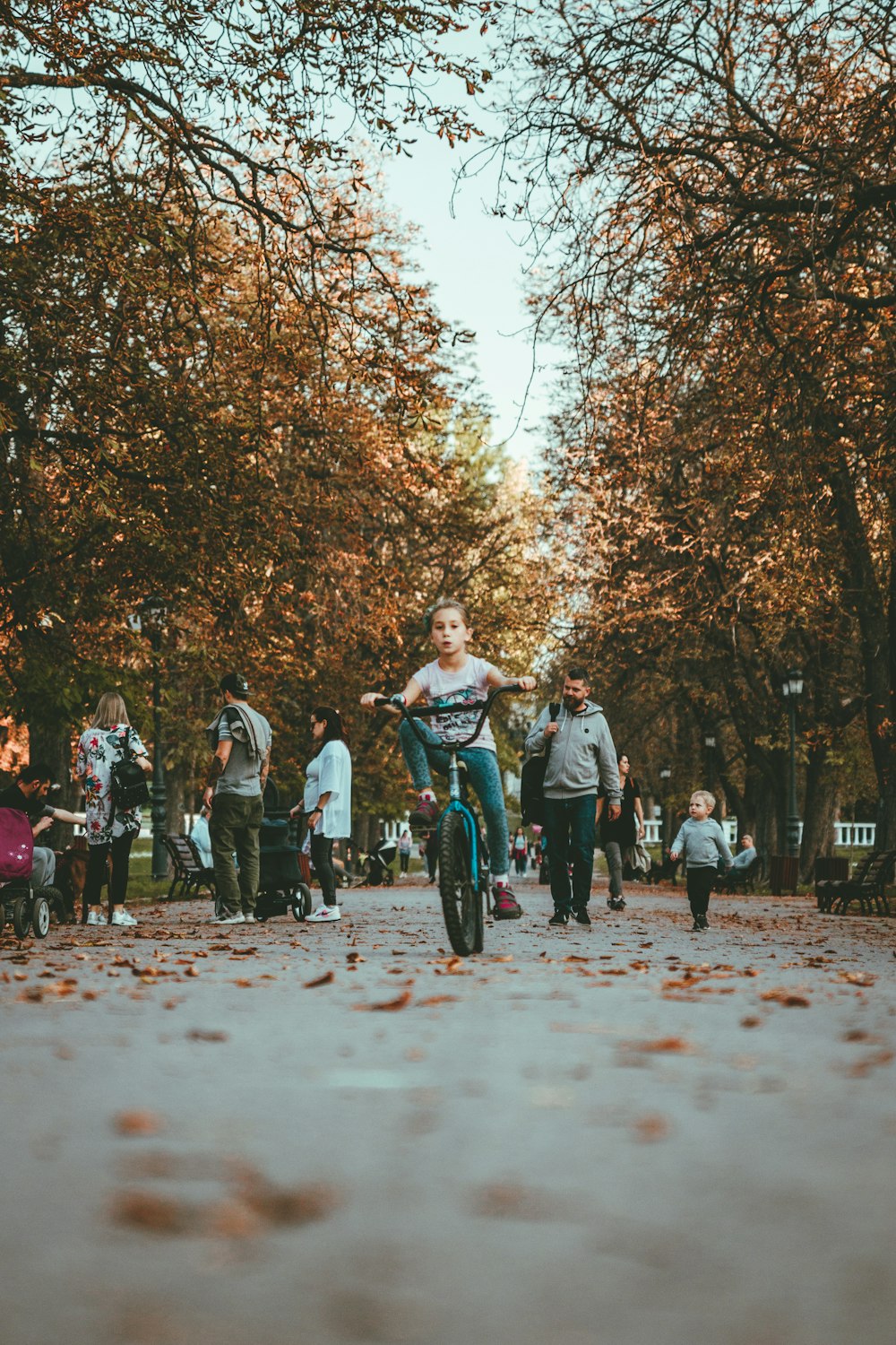 girl riding bicycle on pathway surrounded by people