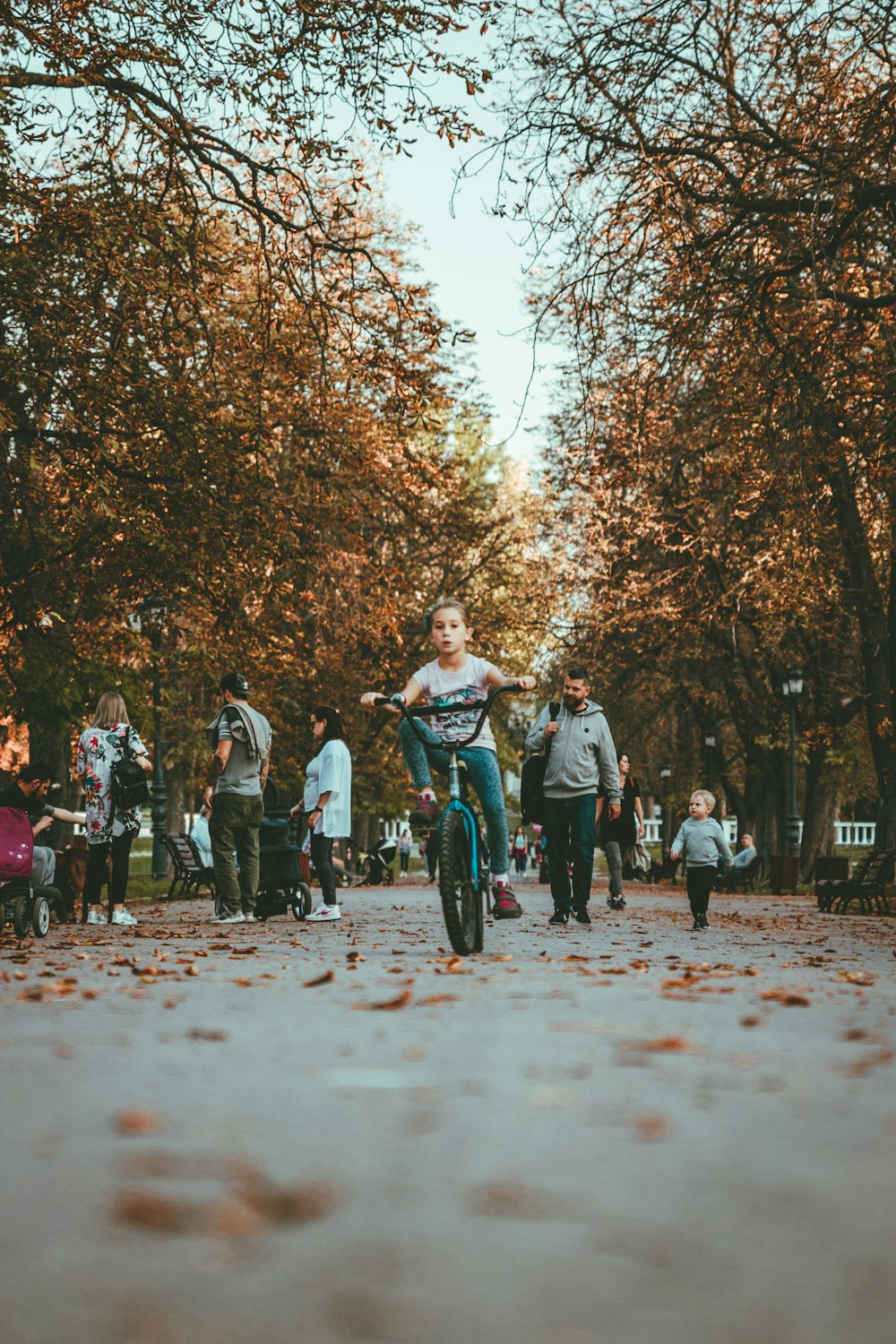 Mädchen fährt Fahrrad auf Weg, umgeben von Menschen