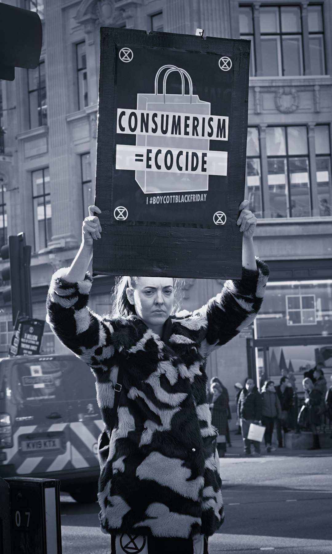 grayscale photography of woman holding banner while standing near buildings and people