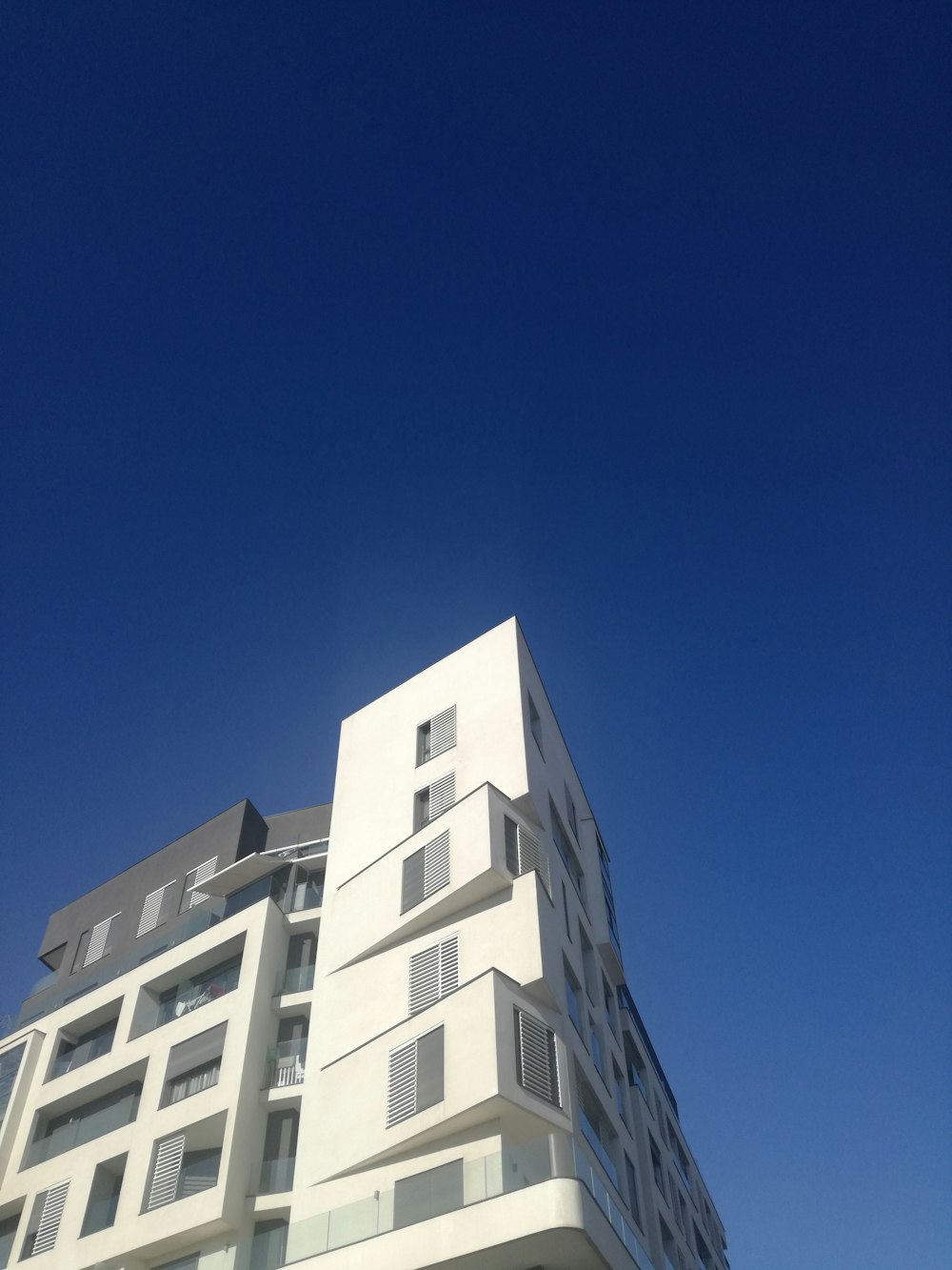 a tall white building with balconies on top of it