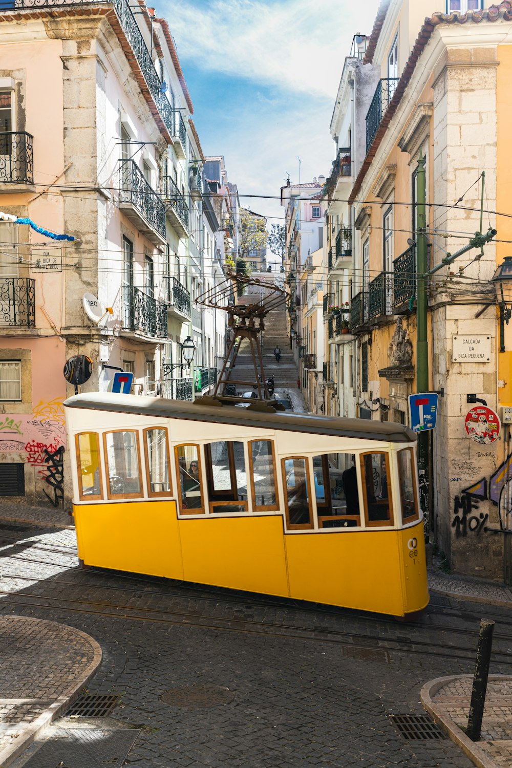 a yellow trolley car traveling down a street next to tall buildings