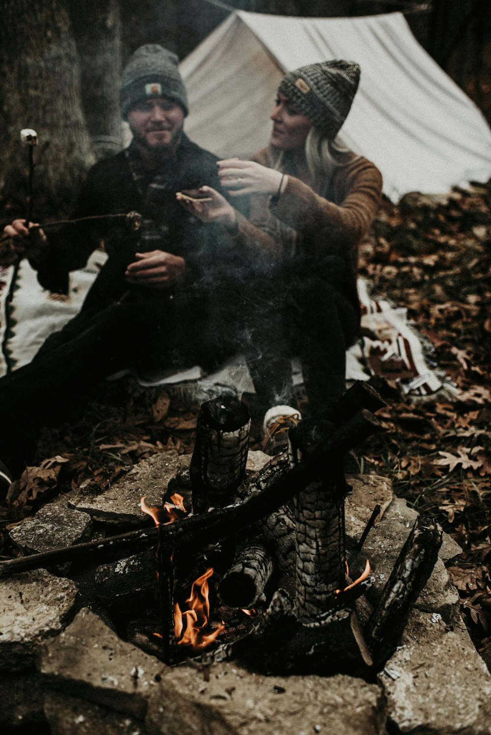 man and woman sitting beside campfire