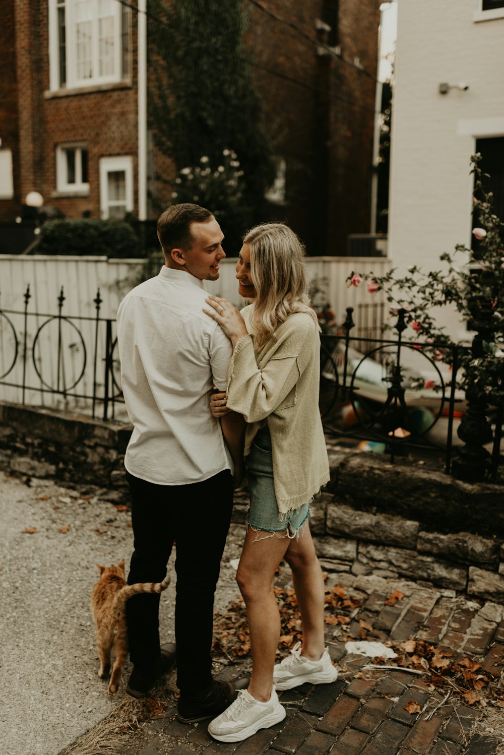 woman hugging man standing beside cat