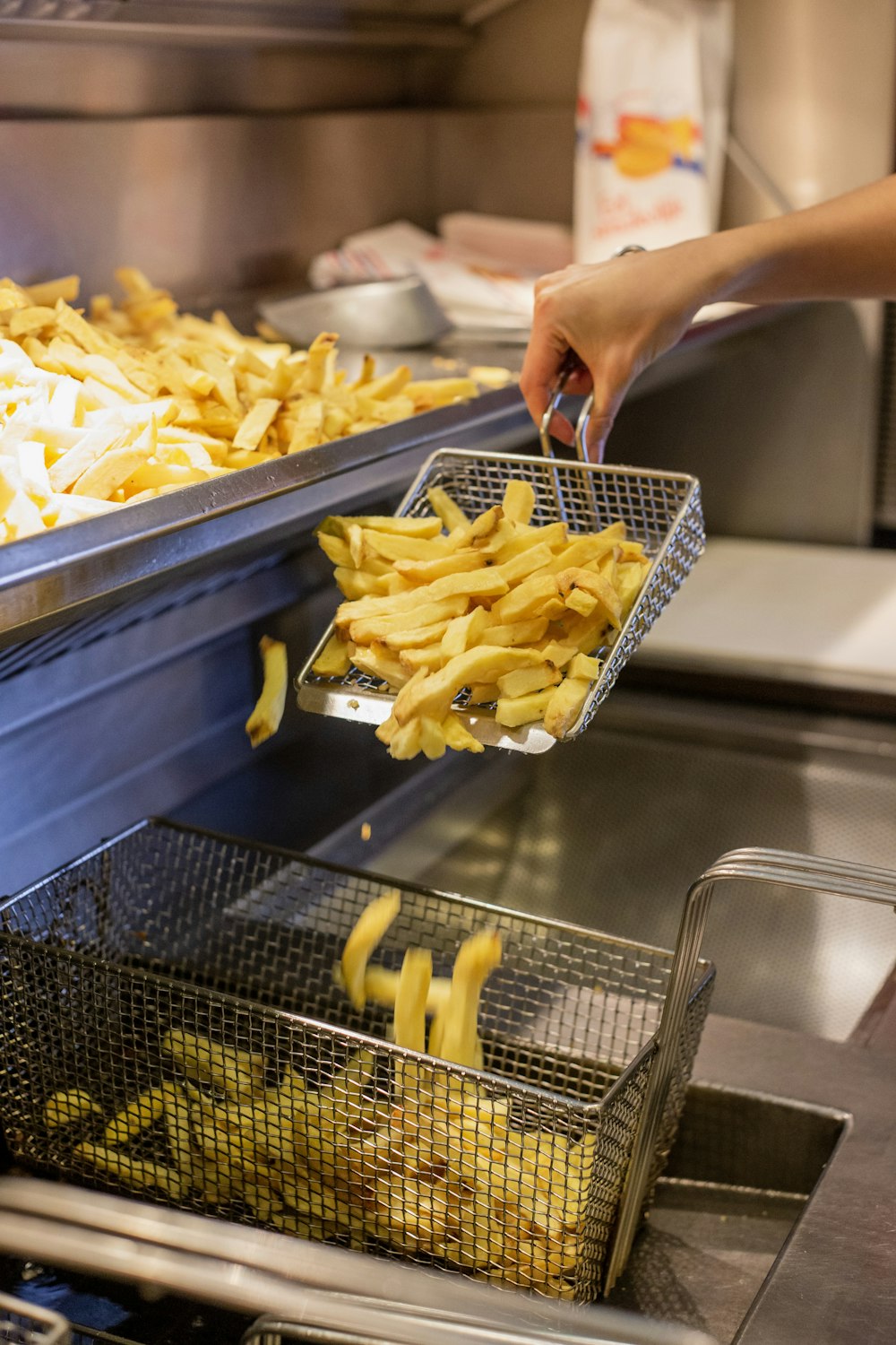 person holding deep frying basket of fries