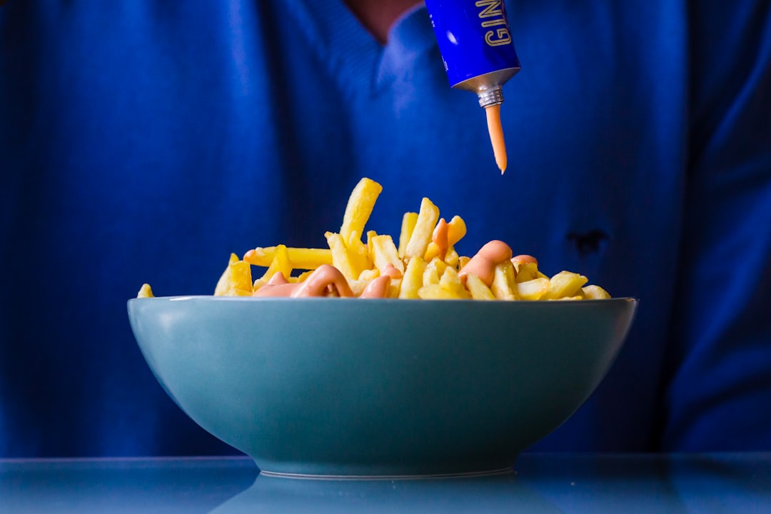 person putting mustard in potato friess