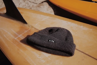 gray Viva knitted cap on wooden surfboard