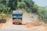 Wide shot of a Foton bus driving along a lush Guanacaste countryside road