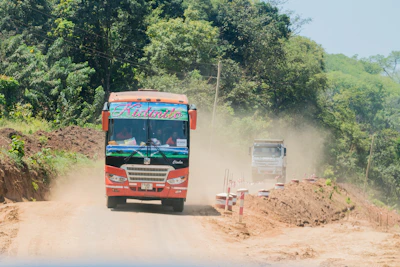 Wide shot of a Foton bus driving along a lush Guanacaste countryside road