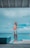 A man stands on a wooden deck next to a tiled infinity pool overlooking a vast ocean. He is wearing white shorts and appears to be adjusting his sunglasses or shielding his eyes from the sun. The sky is partly cloudy with varying shades of blue, and the setting conveys a serene, tropical atmosphere.